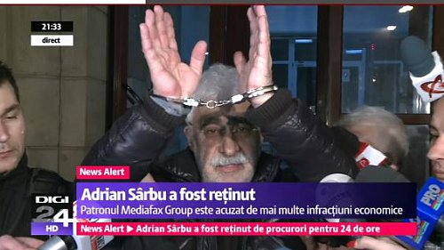 Adrian Sarbu ukazuje na televizní kamery, že skončil v poutech
