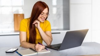Usmívající se žena sedící v kanceláři u počítače