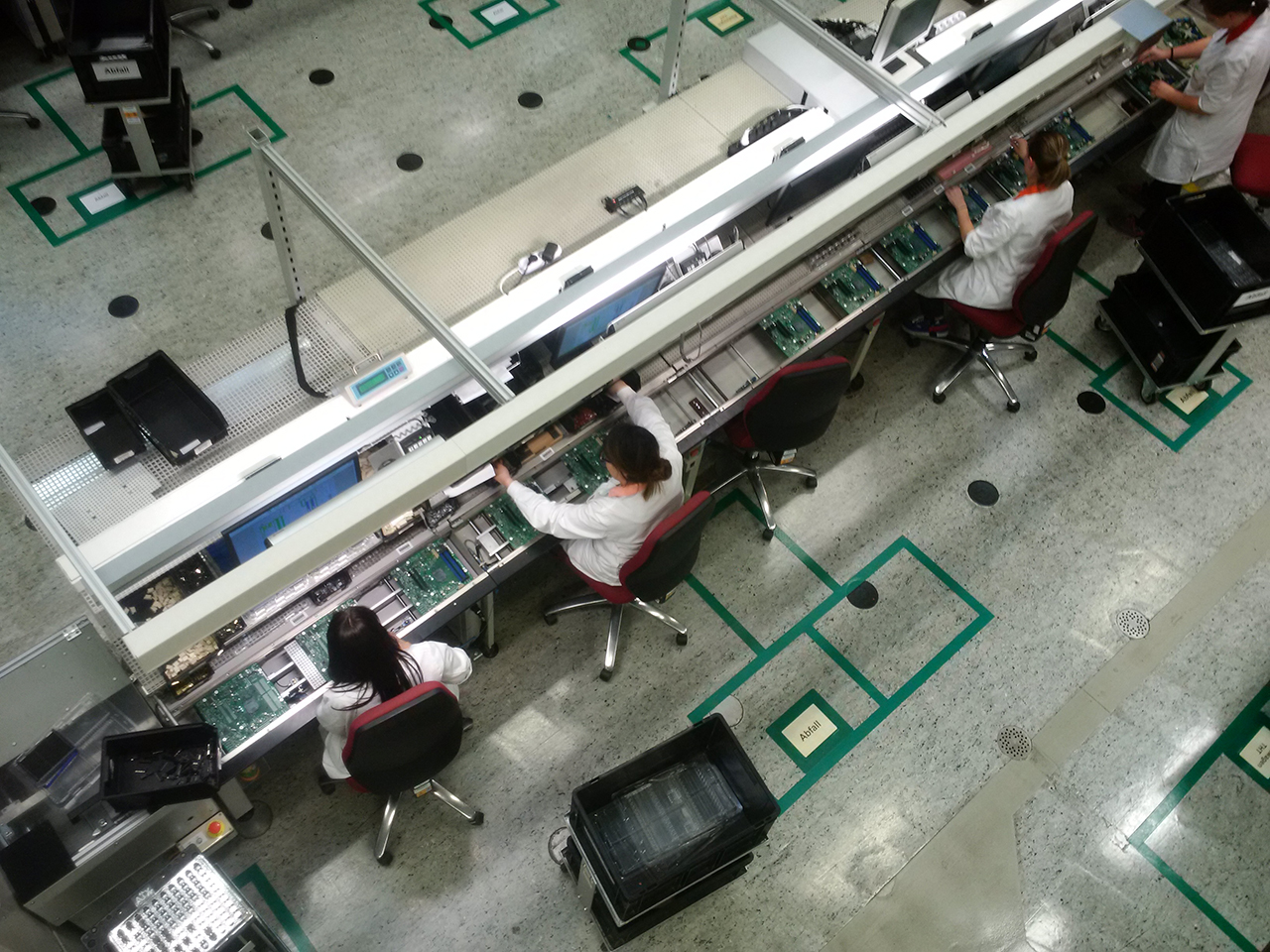 Komponenty jako konektory či baterie na základní desky vkládají lidé.